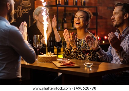 Group of friends celebrating birthday in a cafe behind bar counter