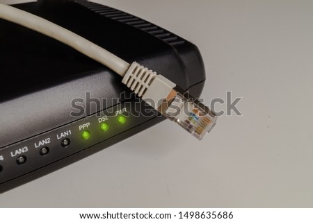 Black dsl modem or router with a network cable on a table. Concept picture for internet, wlan or mobil connections. Royalty-Free Stock Photo #1498635686
