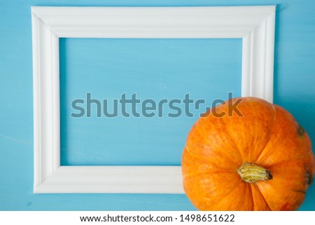 Orange pumpkins with white frame for picture on blue wooden background Thanksgiving and Halloween concept. View from above. Top view. Copy space for text and design