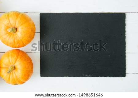 Orange pumpkins on wite wooden background and black slate stone surface. Thanksgiving and Halloween concept. View from above. Top view. Copy space for text and design