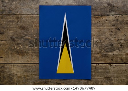 Flag of Saint Lucia on wooden board. Paper Flag of Saint Lucia on wooden table.