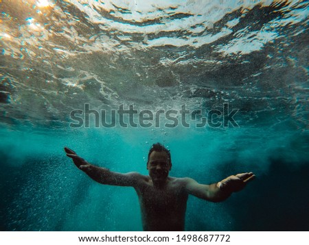 Underwater photo of man emerging from the blue water