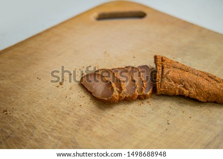 food concept picture of basturma Caucasus region national horse meat dish on wooden cutting board and white studio background with empty space for copy or text