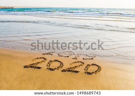 Happy New Year 2020 text on the sea beach. Abstract background photo of coming New Year 2020 and leaving year of 2019