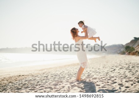 Happy family on the beach. Mother holding her daughter and laughing. Summer holidays