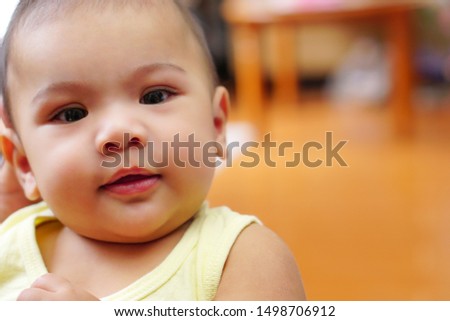 An Asian little cute baby (about 4-6 months) looking at camera and smiling happiness. The concept of love, care, empathy, lovely, cute, adorable and pretty.