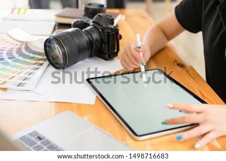 Cropped shot of young freelance graphic designer hand working with stylus pen on mockup white screen tablet computer for creative design project.