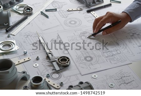Engineer technician designing drawings mechanical parts engineering Enginemanufacturing factory Industry Industrial work project blueprints measuring bearings caliper tools Royalty-Free Stock Photo #1498742519