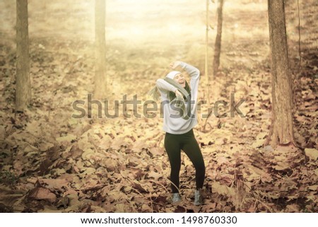 Picture of Asian young woman looks happy while dancing in the autumn park with dried autumn foliage