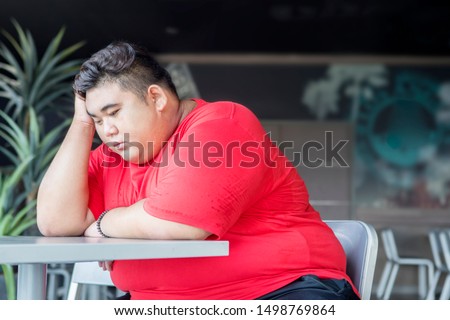 Picture of overweight man looks desperate while sitting in the restaurant