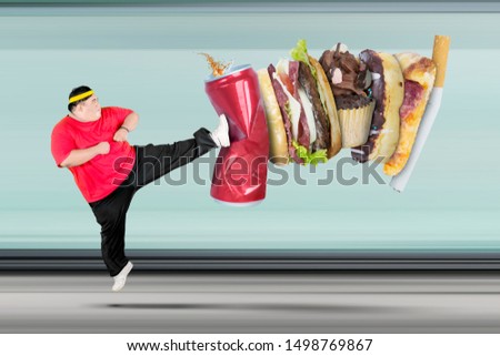 Picture of overweight man wearing sportswear while kicking soft drink and fast food
