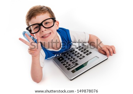 Toddler boy lying on the floor with a big calculator and holding up three fingers.