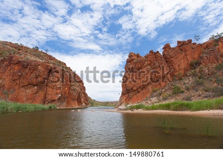 The Finke river flows through the Glen Helen Gorge with left and right  red solid rock formations of the red center of the Northern Territory Australia Royalty-Free Stock Photo #149880761