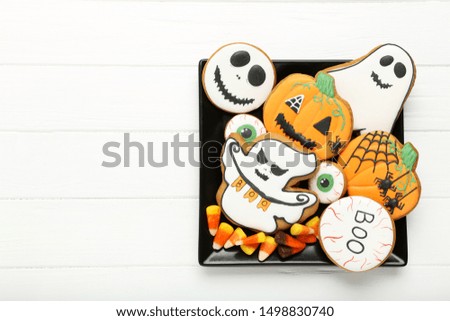 Halloween gingerbread cookies with candies in plate on white wooden table