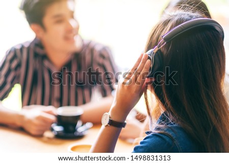 Closeup image of friends enjoyed talking, listening to music with headphone and drinking coffee together in cafe