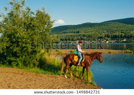 girl on a brown horse by the pond