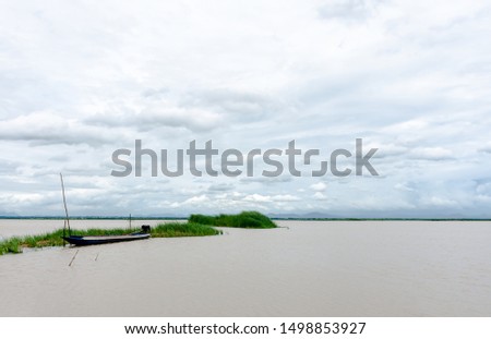 Fishing boats are parked on the vast lake shore. With clouds floating in the sky and the mountains in fro