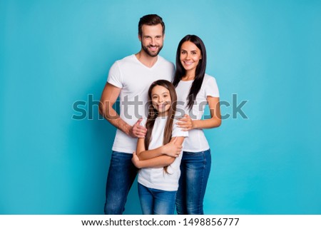 Portrait of lovely family looking with toothy smile wearing white t-shirt denim jeans isolated over blue background