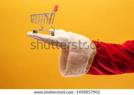 Santa Claus and the supermarket, he is showing a mini cart. Christmas and shopping concept.