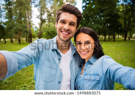 Close up photo of charming spouses making photo hugging embracing wearing denim jeans shirt outside in forest