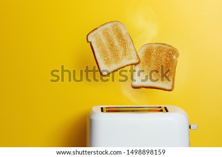 Slices of toast jumping out of the toaster against yellow background. Royalty-Free Stock Photo #1498898159