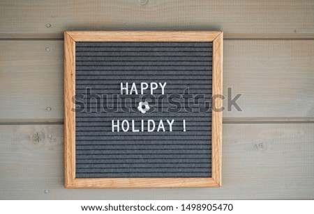 felt Board with text in English happy holiday on a gray wooden wall