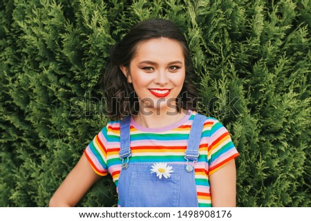 Outdoor portrait of happy young asian woman, posing outside, wearing colorful t-shirt