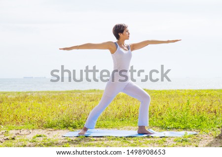 Pretty woman doing yoga exercises posture at the beach under the palm trees on a beautiful day