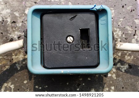 Close up photography of a damaged push-button switch housing on a concrete wall