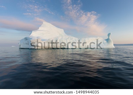 Icebergs in front of the fishing town Ilulissat in Greenland. Nature and landscapes of Greenland. Travel on the vessel among ices. Phenomenon of global warming. Ices of unusual forms and colors. 