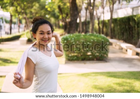 Portrait of Asian attractive beautiful smile young woman runner hold towel to wipe sweat at outdoor park for sport running workput. Jogging exercise, bodybuilding, healthy lifestyle.