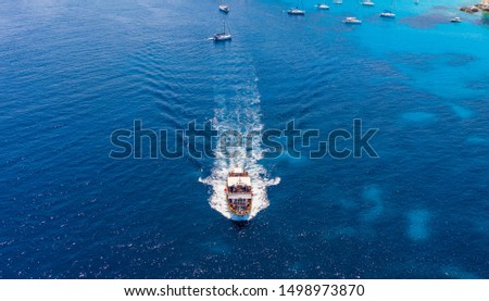 Aerial shot of a passenger boat full of people leaving from Voutoumi beach, Antipaxos, Greece