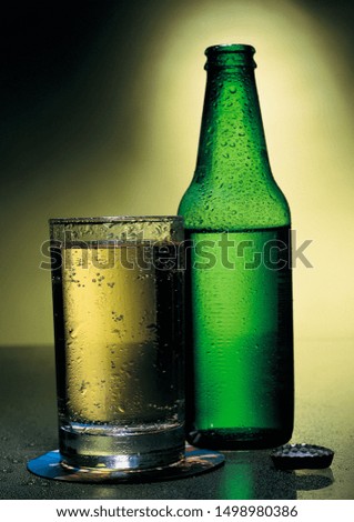 Close up picture of a green bottle and a glass filled with juice 