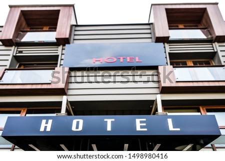 Neon Sign with the word Hotel under white sky background. signboard hotel on the wall of the house