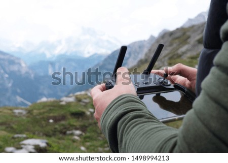 a man holds a remote control from a drone in the background of a mountain landscape, the theme of outdoor activities and technology
