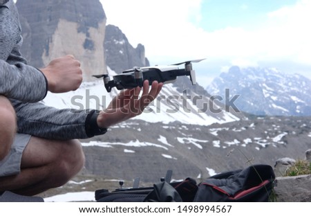a man launches in his hands a doron for video shooting in the mountains against the background of a mountain landscape, the theme of active leisure, hobbies and videos
