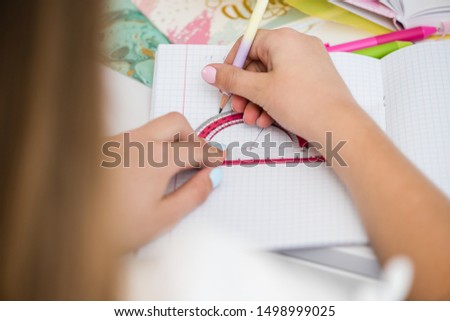School girl hand hold pink protractor rule up view