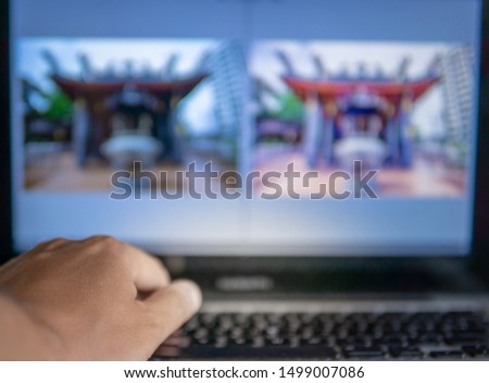 Hand in the foreground and blurred computer with post production of photos