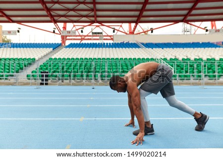 young ambitious sportsman standing on the high start position, full length side view photo. copy space, health and body care
