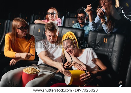 blonde guy splitting popcorn to his girlfriend's knees while watchin film. close up photo