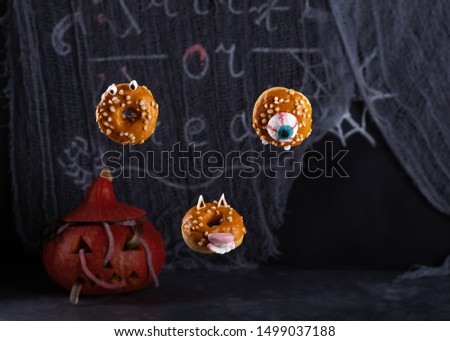 Scary Halloween donuts with teeth and eyes on dark background. Halloween food and decoration.