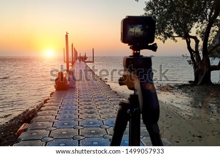 Camera mounted on a tripod photograph couple on the pier and sunrise