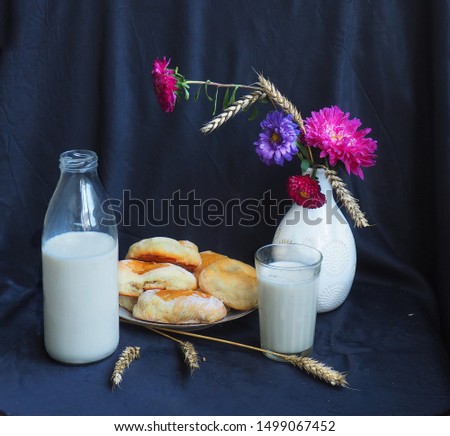 The picture was taken in September 2019.In the picture a vase of flowers, a plate of cakes.Standing next to the bottle of milk,a glass of milk.