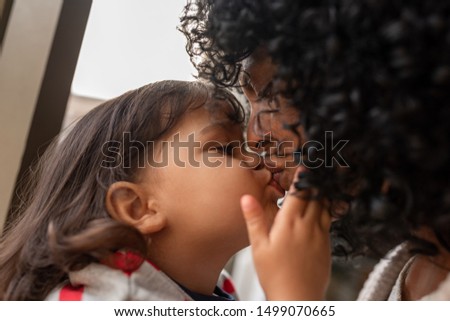 Closeup of an adorable little girl kissing her loving mother while spending time together at home