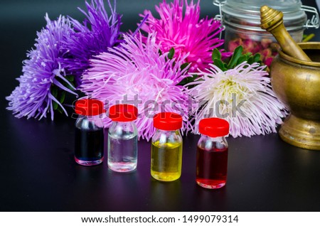 Glass bottles of essential oil with fresh flowers on black background. Studio Photo