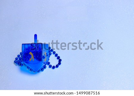 Blue dreidel and beads against a light blue sparkly background