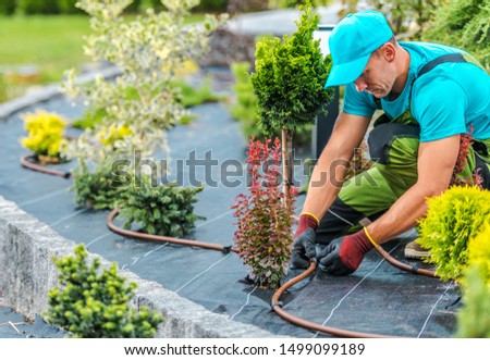 Professional Caucasian Gardener Building Plants Irrigation System in Developed Garden. Industrial Theme. Royalty-Free Stock Photo #1499099189