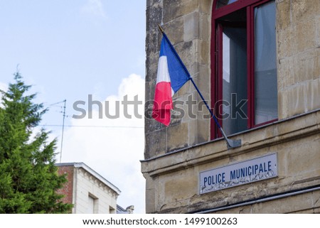 A French flag hung on the window of the municipal police station in Valenciennes, France. Shot in 2019.