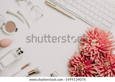 Computer, pink dahlia flowers, notepad paper blank and women's accessories on white office table. Modern minimalist business blog template. Flat lay. Top view. Copy space.