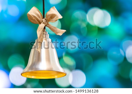 Golden christmas bell on the pantone bleached coral color background with bokeh lights and copy space.